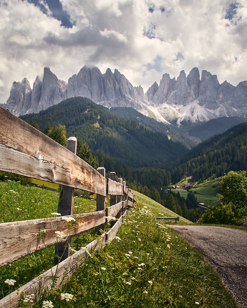 Free Photo vertical shot of a wooden fence with high rocky cliffs in funes valley, st. italy