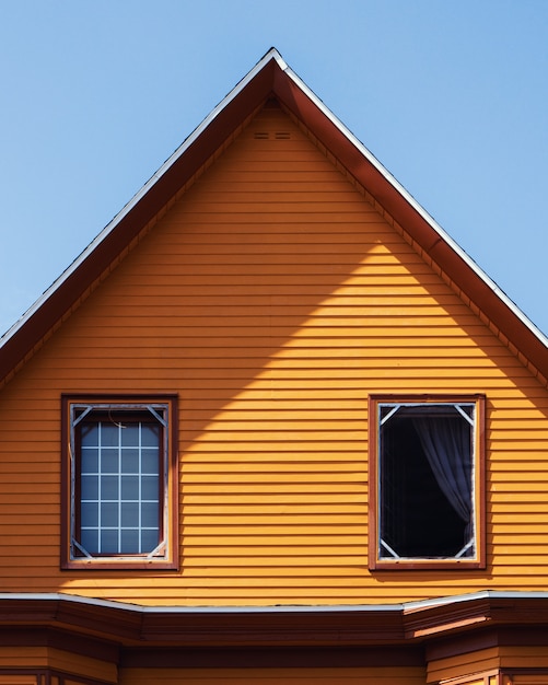 Vertical shot of a wooden orange house under the clear blue sky