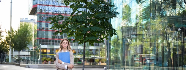 Free Photo vertical shot of young businesswoman in beige suit holding documents in hands looking confident at