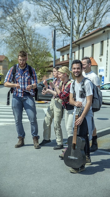 Vertical shot of young happy friends singing and dancing in the street