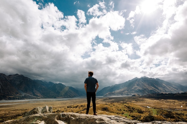 Free photo vertical shot of a young male staring at the mountains on a sunny day