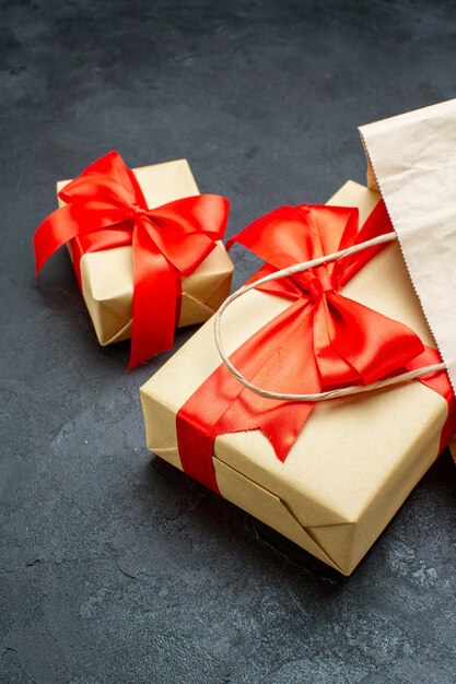 Vertical view of beautiful gifts with red ribbon on a dark table