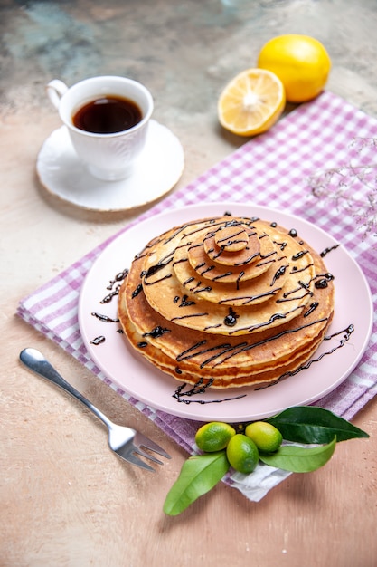 Vertical view of classic delicious pancakes decorated with chocolate syrop on pink stripped towel