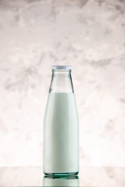 Vertical view of closed and filled with milk glass bottle on white smoke background with free space