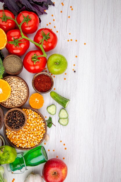 Vertical view of collection of fresh foods and spices vegetables on white table