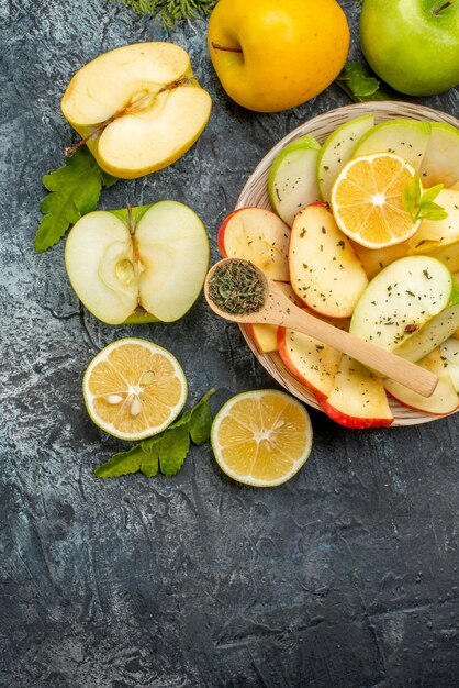 Vertical view of collection of fresh natural organic fruits on a white plate cutlery set cinnamon limes on the left side on a dark background