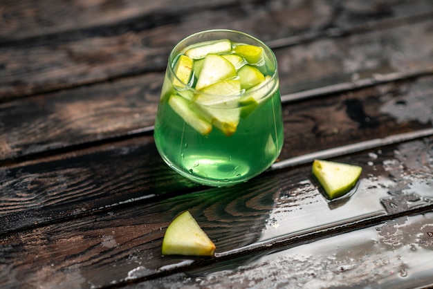 Free photo vertical view of delicious juice in a glass with apple limes in it on dark background