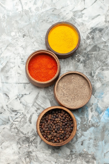 Free Photo vertical view of different spices in brown bowls on gray background