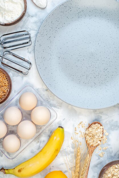 Vertical view of empty gray plate and ingredients for the healthy food set on ice surface