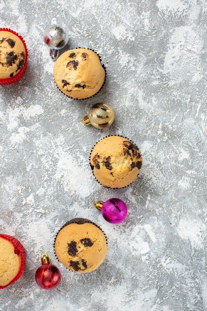 Vertical view of empty space among freshly baked delicious small cupcakes and decoration accessories on ice surface