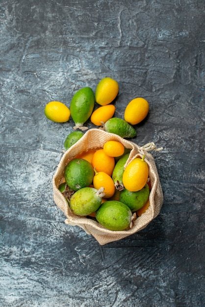 Vertical view of fresh kumquats in a small white bag and on gray background