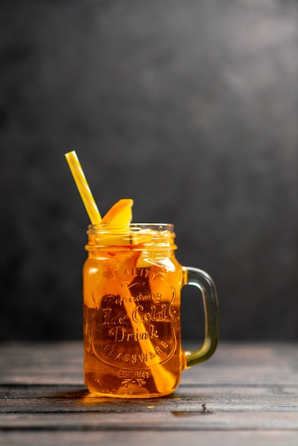 Vertical view of fresh natural delicious juice in a glass with tube in it on black background