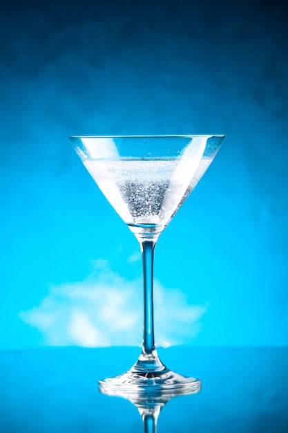 Free photo vertical view of glass goblet for wine standing on the right side on blue background