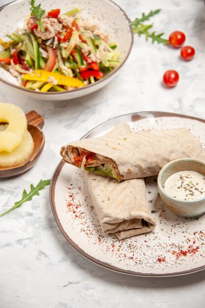 Vertical view of healthy vegan salads dried pineapples and lavash wraps on stained white surface