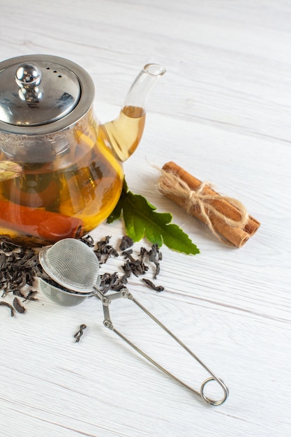 Free photo vertical view of herbal tea in a glass pot and cinnamon limes on white background