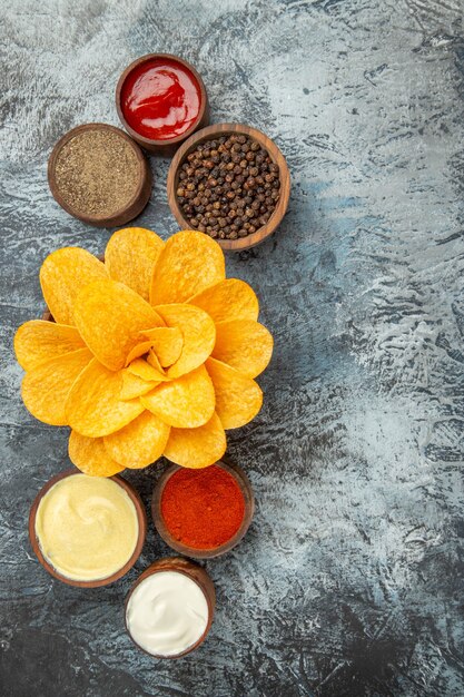 Vertical view of homemade potato chips decorated like flower shaped in a brown bowl on gray background