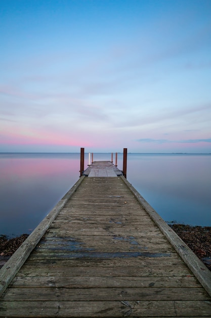 Free Photo vertical view of a long wooden pier near the ocean under the pastel-colored sky