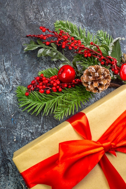 Vertical view of new year gift with red ribbon and acessories decorations on dark surface