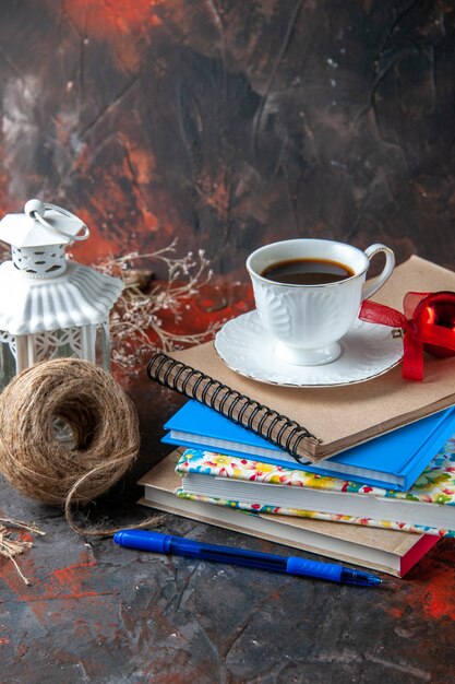 Vertical view of office suppliances and pen cinnamon limes conifer cone and a cup of tea a ball of rope on dark background