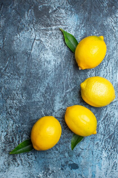 Vertical view of organic natural fresh lemons with leaves on dark background