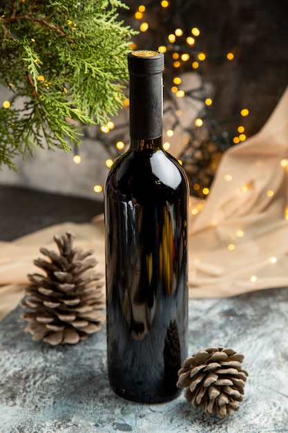 Vertical view of red glass wine bottle for family celebration and fir branche conifer cones