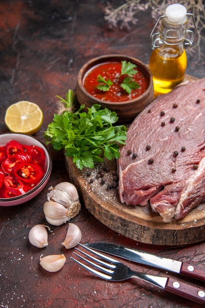 Vertical view of red meat on wooden tray and garlic green ketchup and chopped pepper oil bottle on dark background stock image