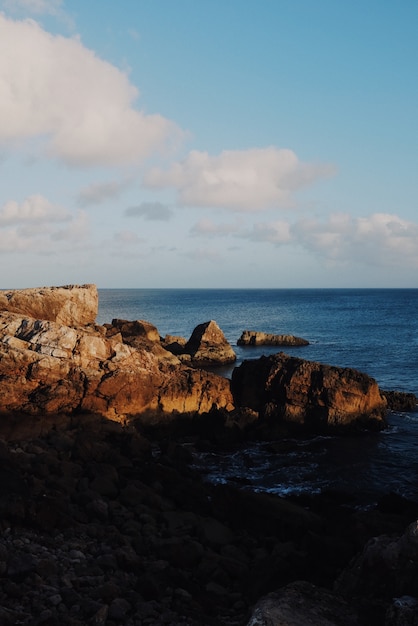 Vertical view of rocks at sunrise with the ocean in the background