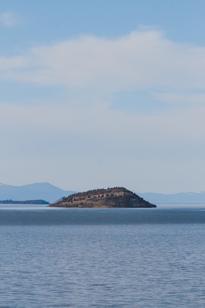 Vertical view of the sea surrounding an island under the cloudy sky at daytime