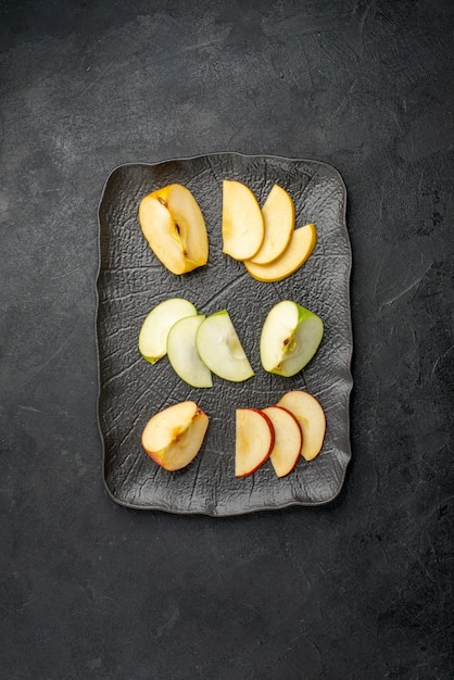 Free Photo vertical view of several types of sliced fresh apples on a black tray on a dark background