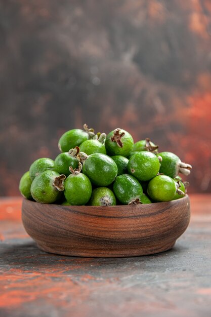 Vertical view of small vitamin bomb green feijoas in a brown wooden pot