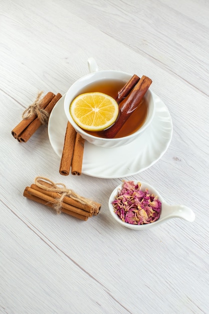 Vertical view of tea break with cinnamon lime and lemon in a cup on white background