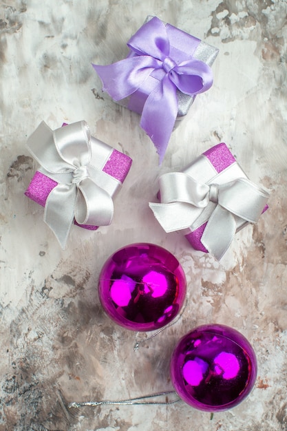 Free photo vertical view of three xsmas gifts for family members and a decoration accessory on the left side on ice background