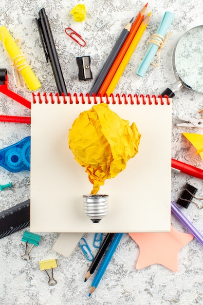 Free Photo vertical view of time torn balloon on spiral closed spiral notebook and various office appliances on white surface