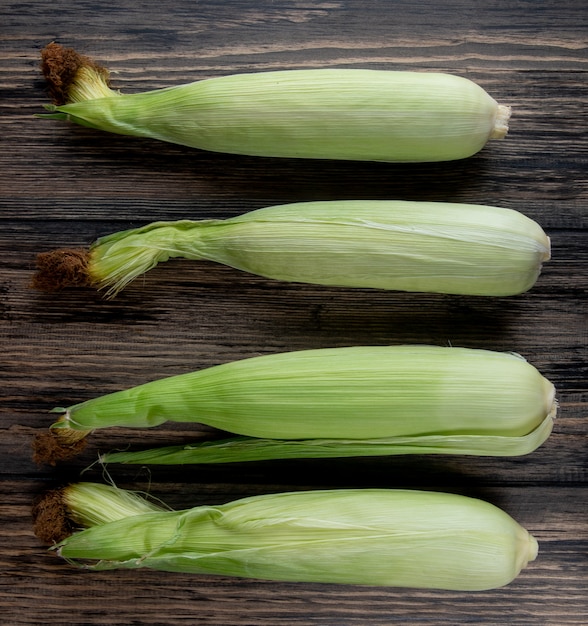 Vertical view of uncooked corns on wooden table