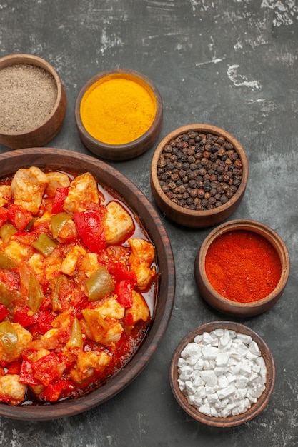 Free photo vertical view of vegetable spicy chicken soup in a brown pot and different spices