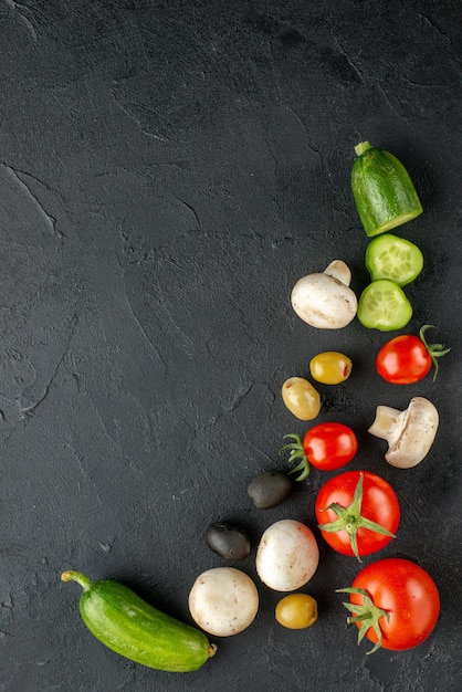 Free Photo vertical view of whole and cut fresh vegetables raw mushrooms on black surface