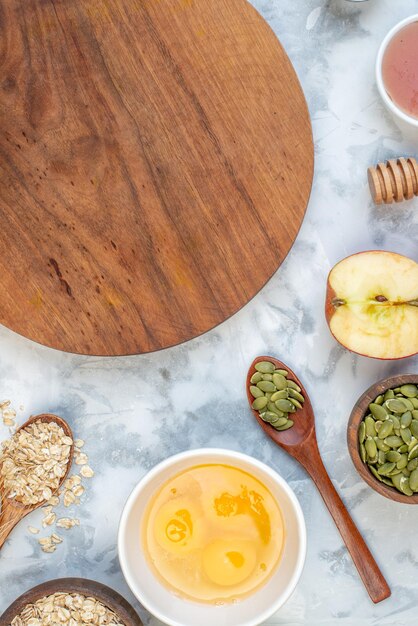 Vertical view of wooden round board and ingredients for the healthy food set on stained white background