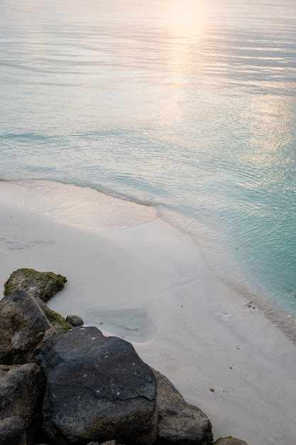 Free Photo verticals shot of a sandy beach with the reflection of the sun in the blue water