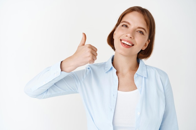 Free Photo very good portrait of businesswoman showing thumb up like and approve say yes and agree standing in blouse on white background