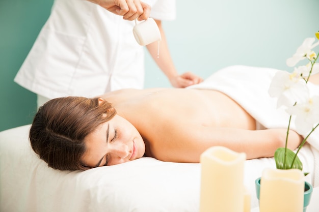 Very relaxed and cute young woman getting a candle massage at a beauty clinic and spa