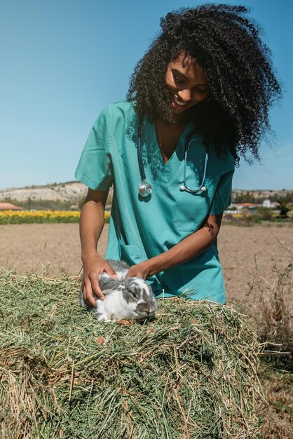 Veterinarian examining a bunny in a hay field