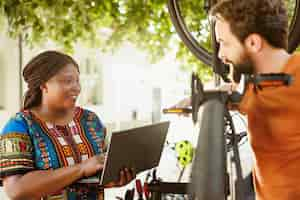 Free photo vibrant couple fixing bike with laptop