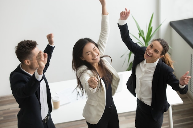 Victory dance concept, excited diverse coworkers celebrating business success