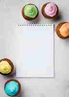 Free photo above view arrangement with glazed muffins and notebook