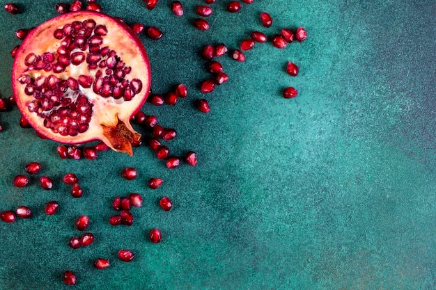 Free photo view  copy space chopped half pomegranate with peeled on a green table