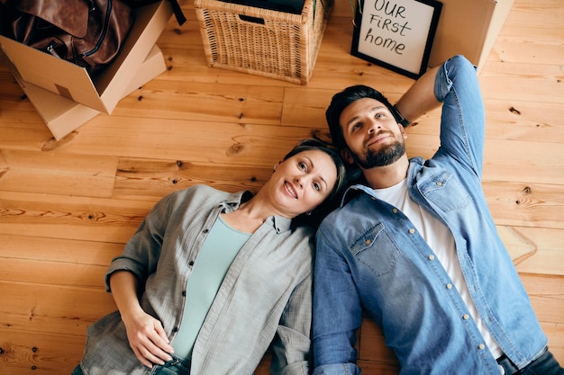 Free photo above view of a couple lying down on floor at their new home