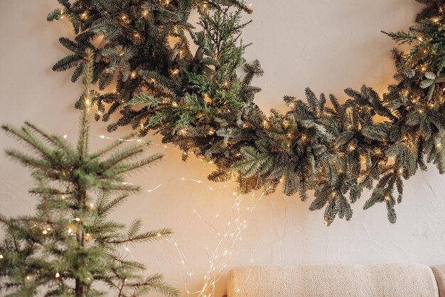 View over decorated artificial fireplace with decorations inside. Handmade paper stars, candles inside. Beautiful coniferous wreath on the top of fireplace. Decorative round mirror over the fireplace.