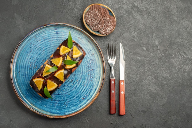 Free Photo above view of delicious cake decorated orange with chocolate and biscuits on black table