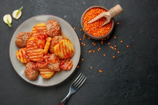 Above view of delicious dinner with potato and meat tomato garlic fork lentil on black