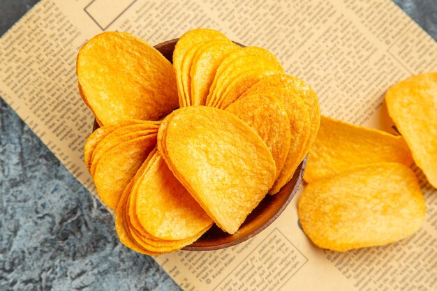 Above view of delicious homemade chips on newspaper on gray table